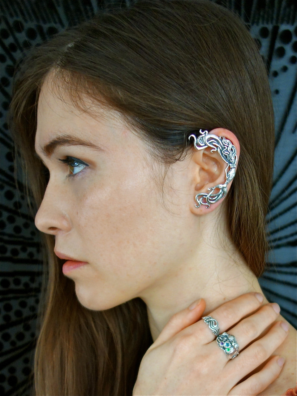 Teresa is modeling the wave rider mermaid ear wrap in silver with the tide pool ring with gem stones, and Nouveau Swirl Ring in silver.