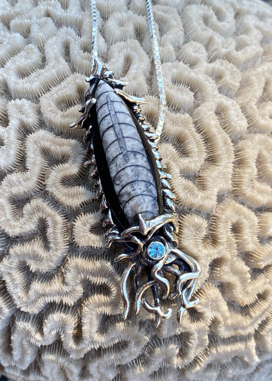 Fossilized Orthoceras Creature Pendant with blue topaz.
