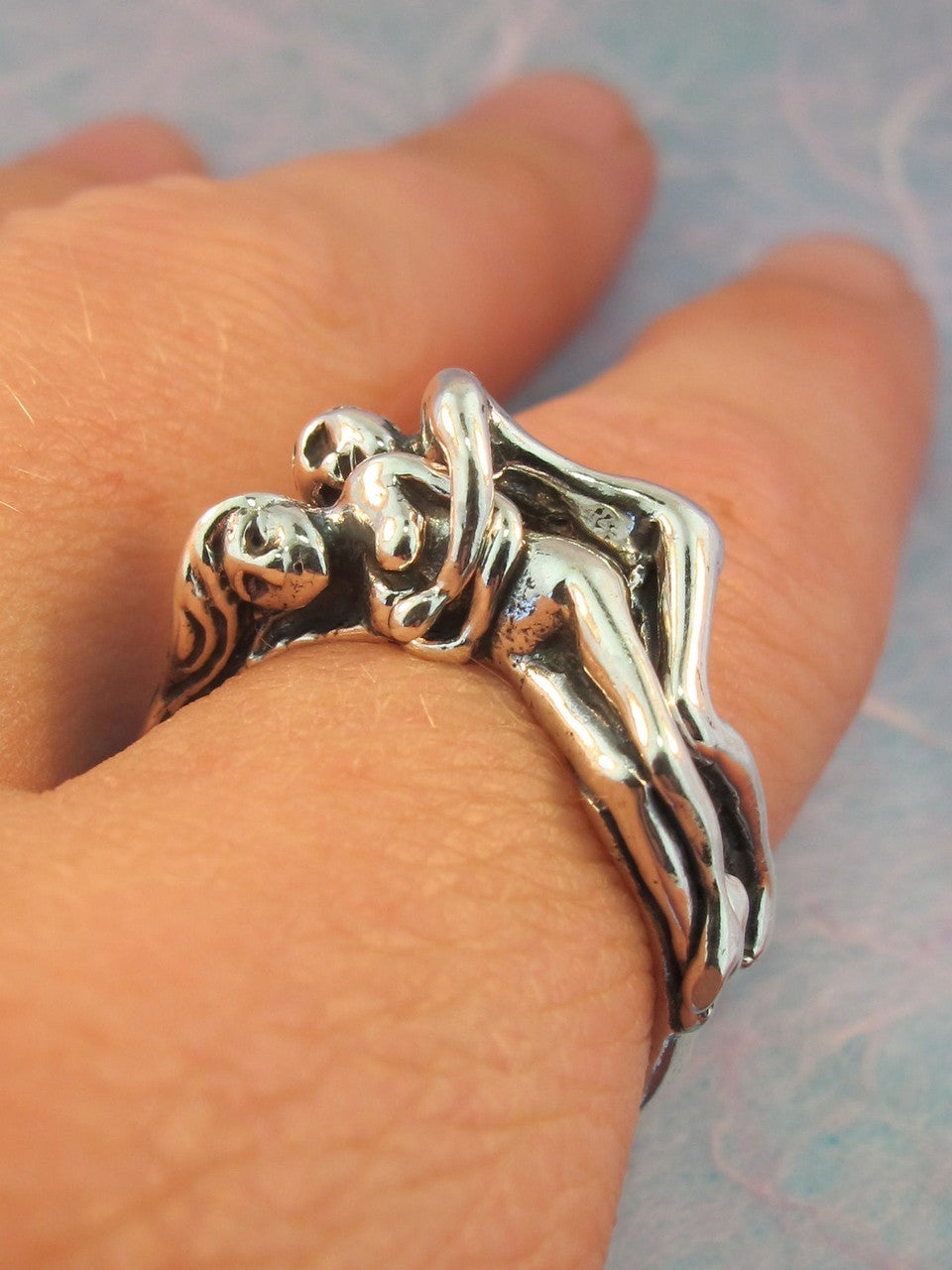 Two spooning lovers embrace in this two part, sterling silver ring.